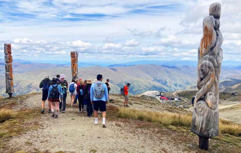 Students walk past totems on a mountain top